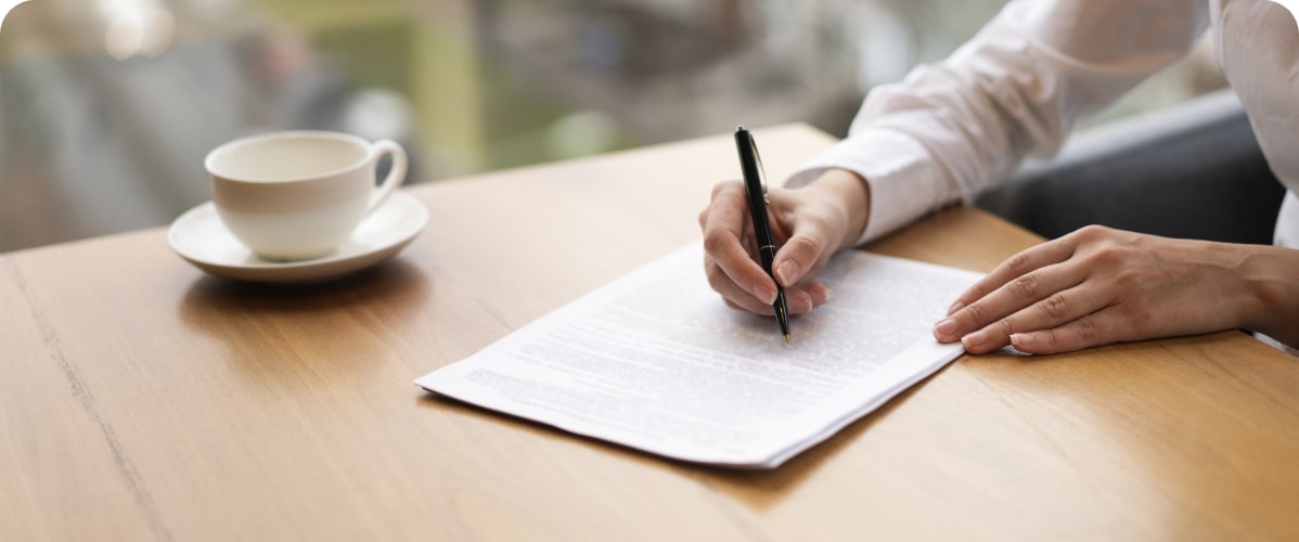 Hand unterschreibt Dokument am Tisch