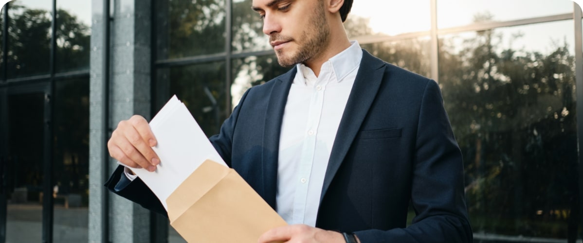 Geschäftsmann mit Mappe vor Bürogebäude
